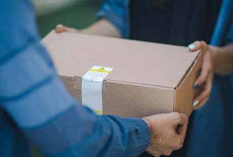 A close up of the hands of a person handing a package
to another person.
